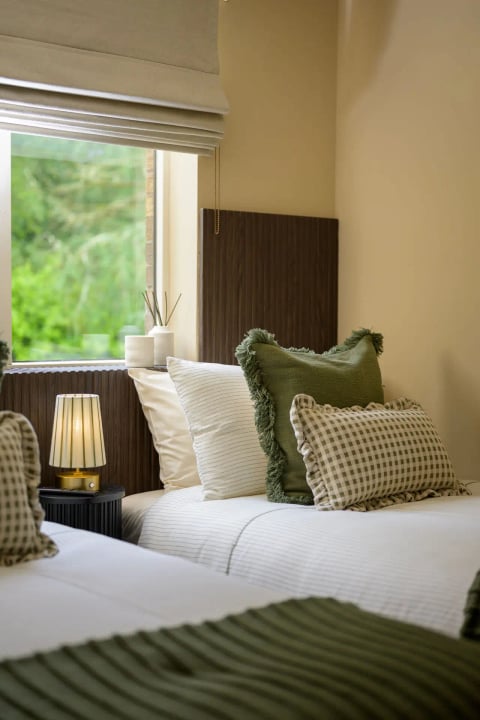 Guest bed with layered cushions by the window
