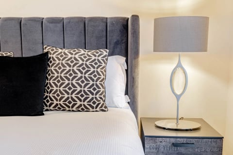 Bedside detail with patterned cushions and sculptural lamp