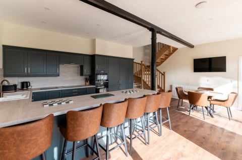 The kitchen island seating eight beside the oak stairs