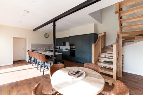 Open-plan kitchen and dining with round table and original beams