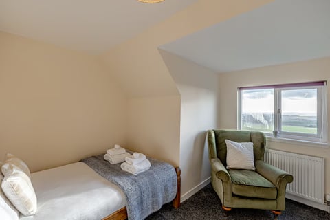 Single bed with green armchair in the eaves