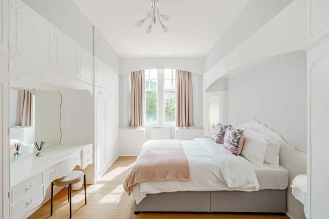 Bedroom with blush throw and fitted wardrobes