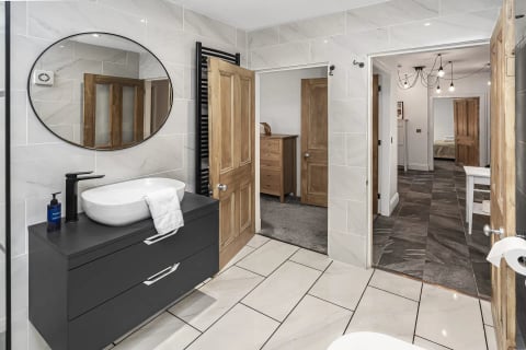 Bathroom vanity with round mirror and black towel rail
