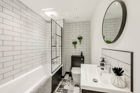 Bathroom with over-bath shower, metro tiles and black-framed screen