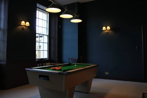 Pool table beneath brass lights in the games room