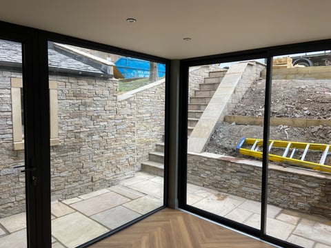 Completed garden room with sliding doors onto a new stone terrace