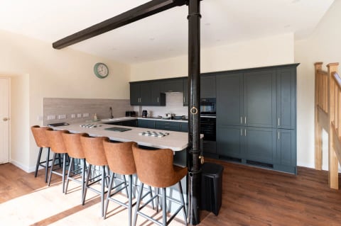 Long breakfast bar with leather stools under the black iron column