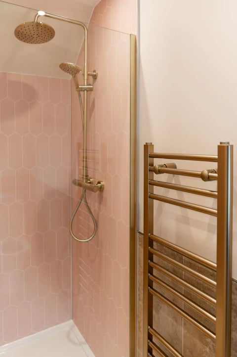 Pink-tiled shower with brass towel ladder