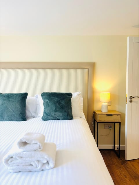 Fluffy white towels folded on a crisply dressed bed