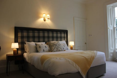 Tartan-headboard bedroom with yellow throw
