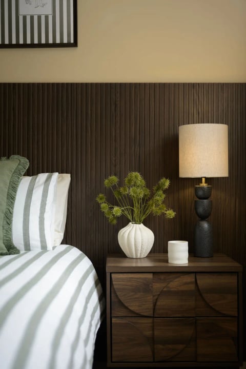 Green striped bedding against the walnut slatted wall