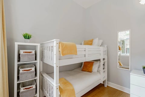 White bunk beds with mustard throws and storage baskets