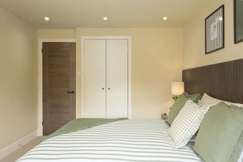 King bed with striped linen facing the fitted wardrobes