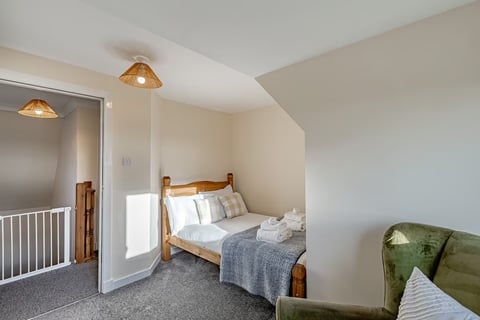 Single bedroom with pine bed and grey throw
