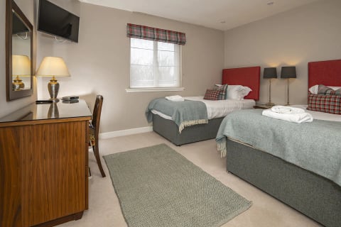 Twin beds with sage runners and desk