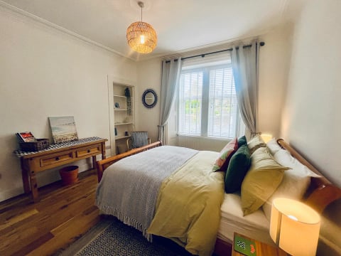 Double bedroom in yellow and green tones with window seat desk