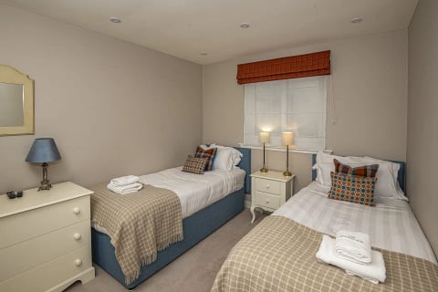 Twin bedroom with tartan cushions and lamps