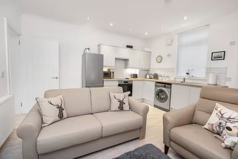 Open-plan living space with cream sofas and modern kitchen behind