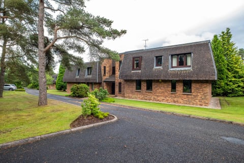 The brick-built lodges seen from the tree line