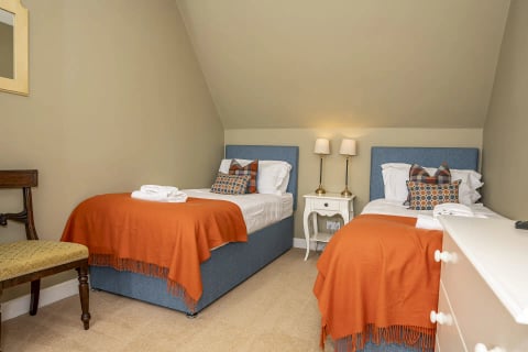 Twin beds with bright orange throws and lamps