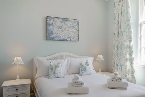 Duck-egg bedroom with rattan headboard and blossom artwork