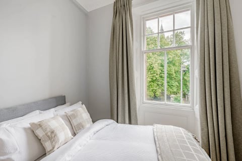 Bed beside the tall sash window