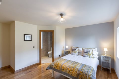 King bedroom with mustard throw and en-suite