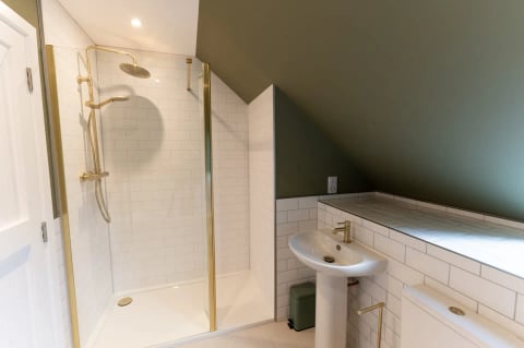 Walk-in shower with gold trim in the eaves bathroom