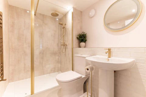 Gold-fitted shower room with round mirror