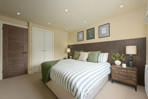 King bedroom with striped bedding and fitted wardrobes
