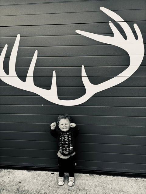 A delighted wee fan beneath the antler mark painted on the Mòrachd workshop door