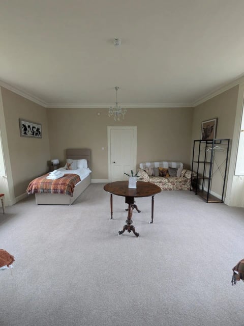 Large twin bedroom with antique table and sofa