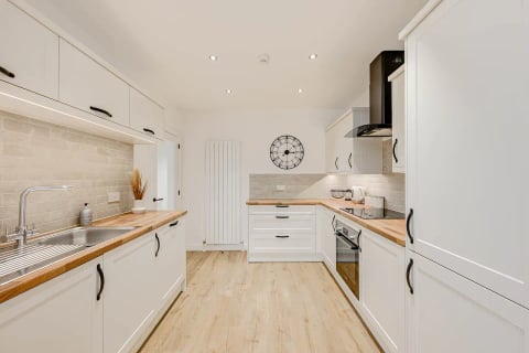 White shaker kitchen with butcher-block worktops and wall clock