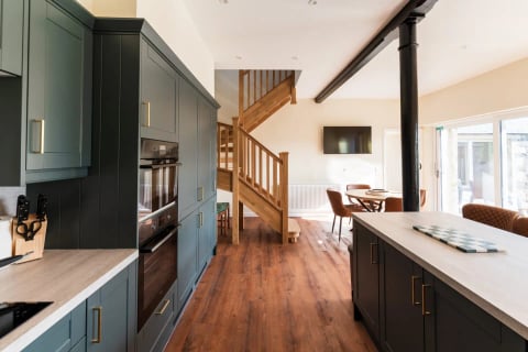 Navy kitchen with double ovens and oak staircase beyond