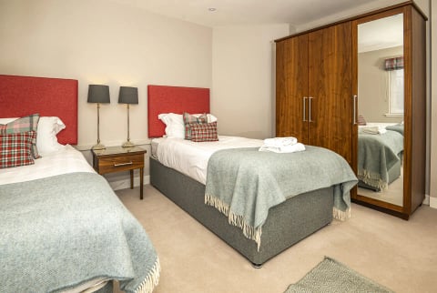 Twin bedroom with red headboard and green throws