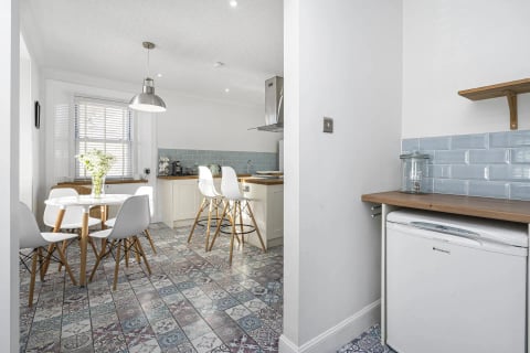 Kitchen-diner with white chairs and patterned floor