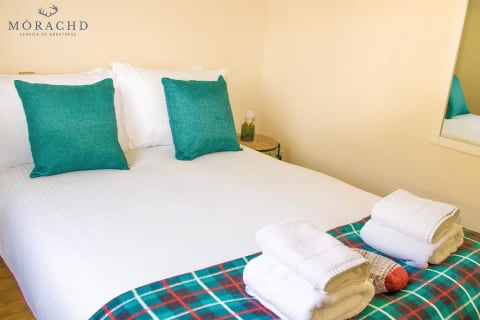 Double bed with teal cushions and fresh towels