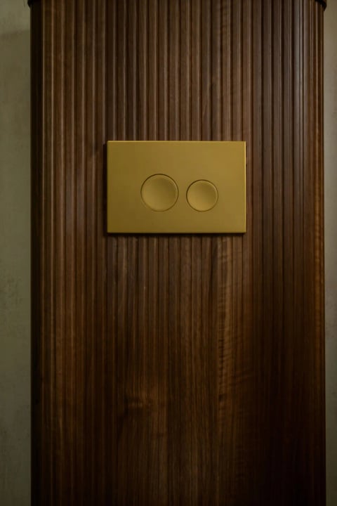 Brushed-gold flush plate on walnut panelling