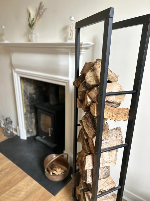White fireplace with stacked logs and ladder