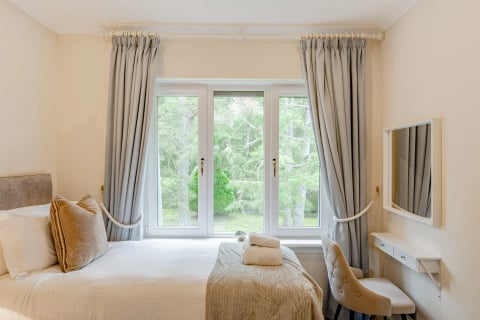Twin bedroom with rope-tied curtains and dressing chair