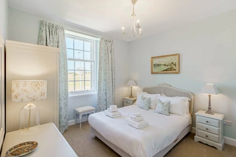 King bedroom with upholstered headboard and garden outlook