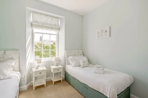 Single bed beneath the sash window with bedside tables
