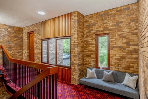 Landing with exposed brick and slatted timber, window seat below