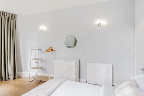 Bedroom with round mirror and white drawers