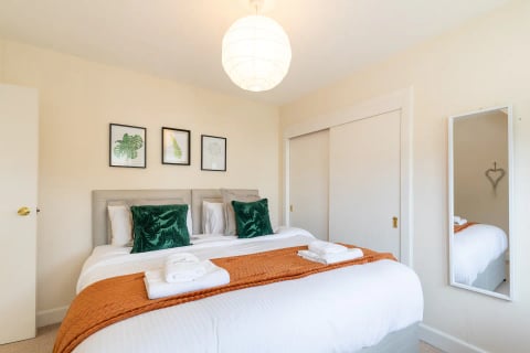 Double bedroom with emerald cushions and orange throw