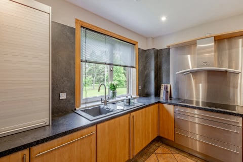 L-shaped kitchen with dark worktops and garden view