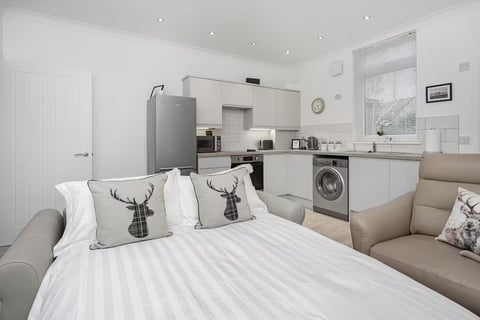 Open-plan living space with cream sofas and modern kitchen behind