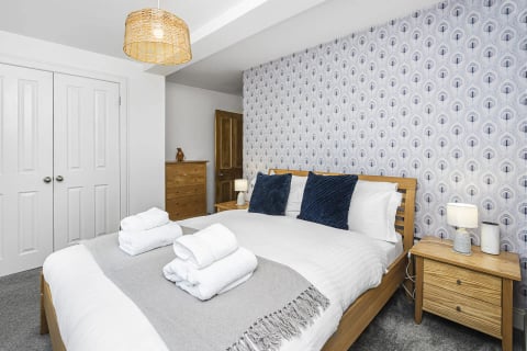 King bed with towels, grey throw and period fireplace