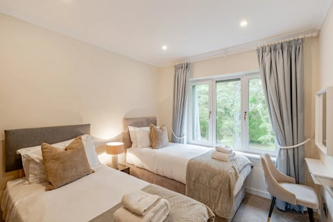Twin bedroom with lamp glow and forest view