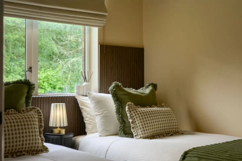 Single bed with green gingham cushions and lamp